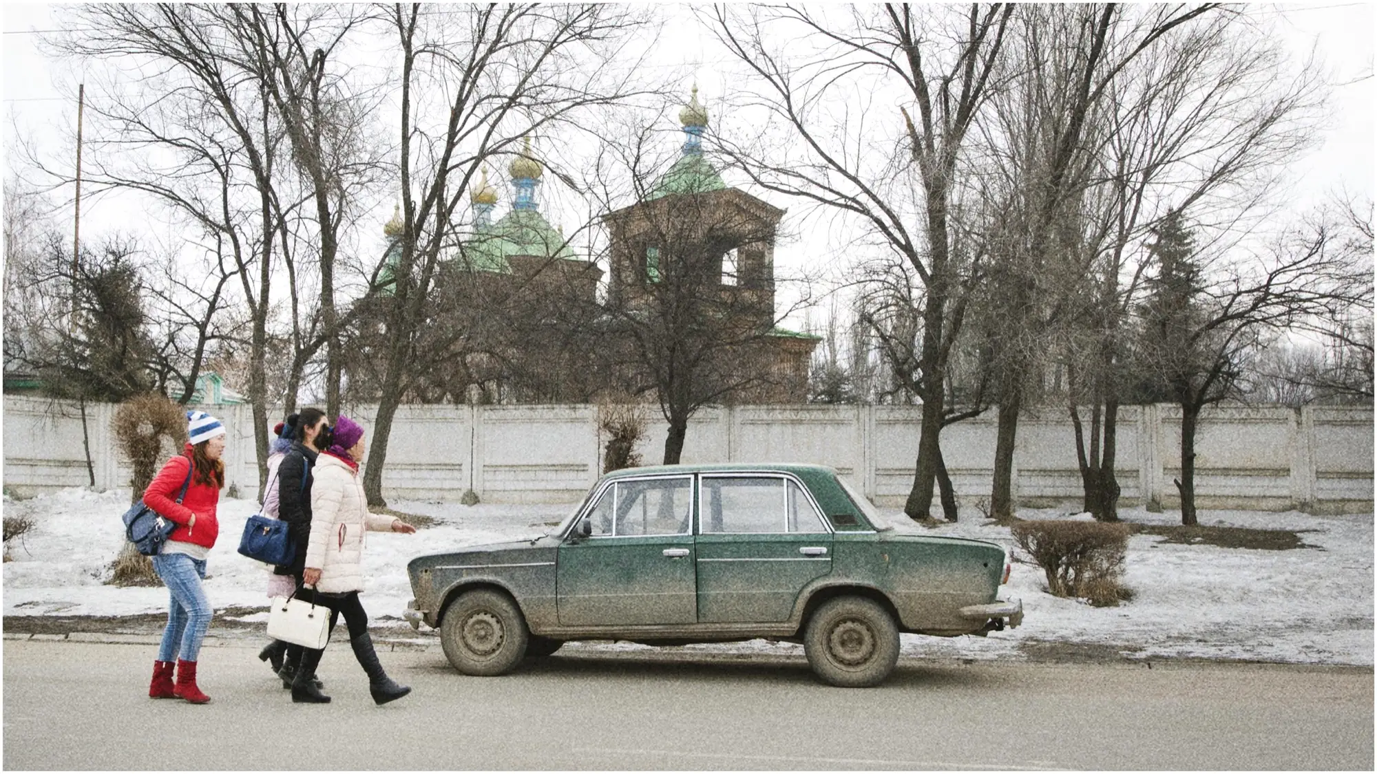 Straat in Karakol met een oude Lada en een houten kerk