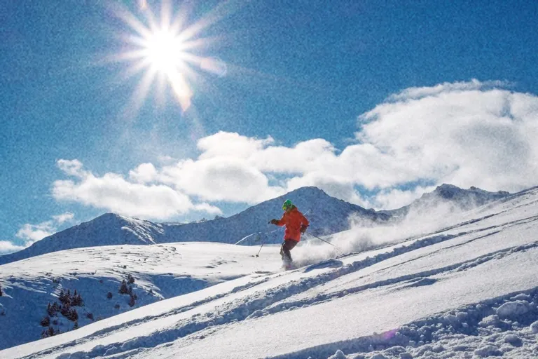 Skiër in de sneeuw onder een felle zon