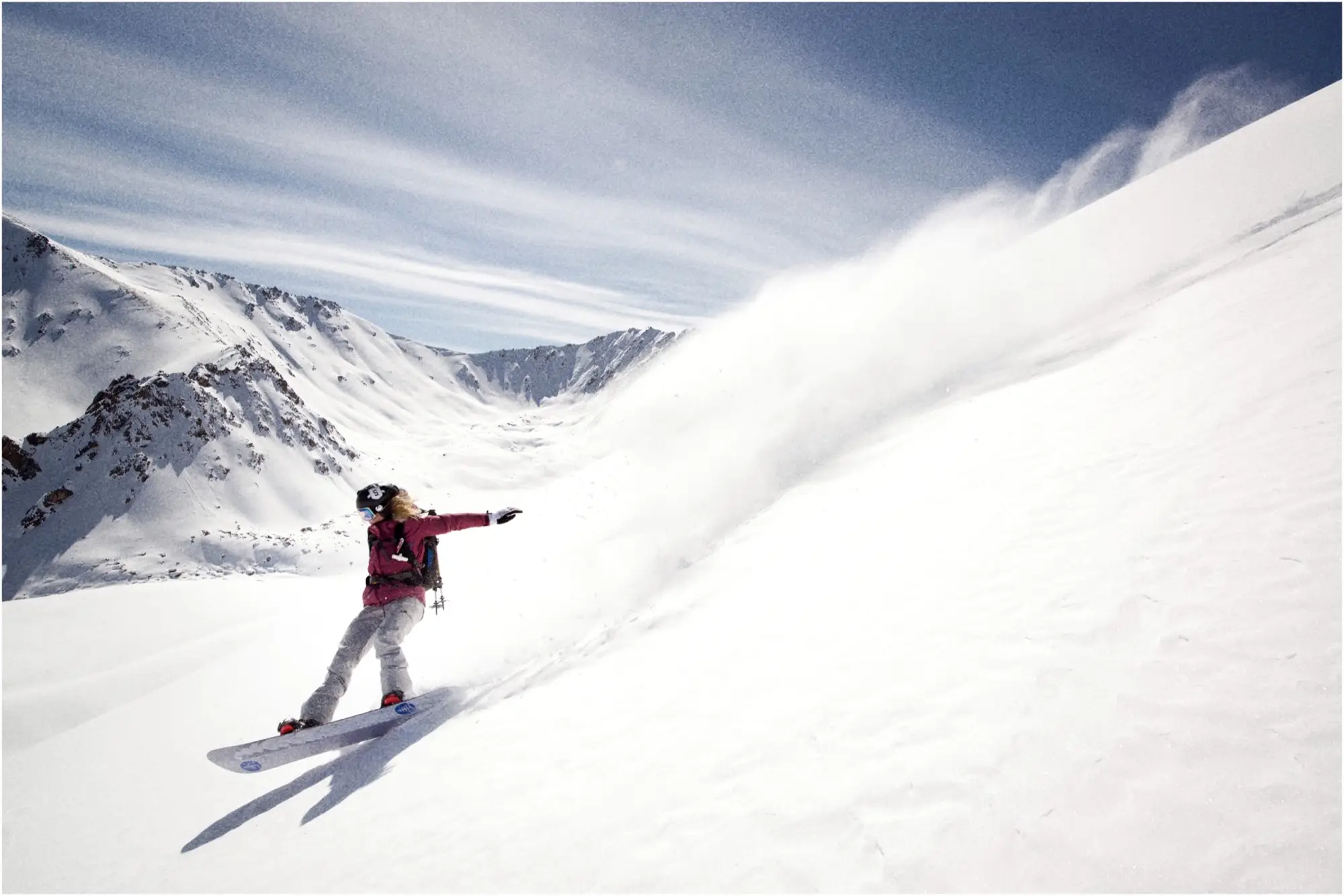 Snowboarder trekt een wolk sneeuw op een steile helling