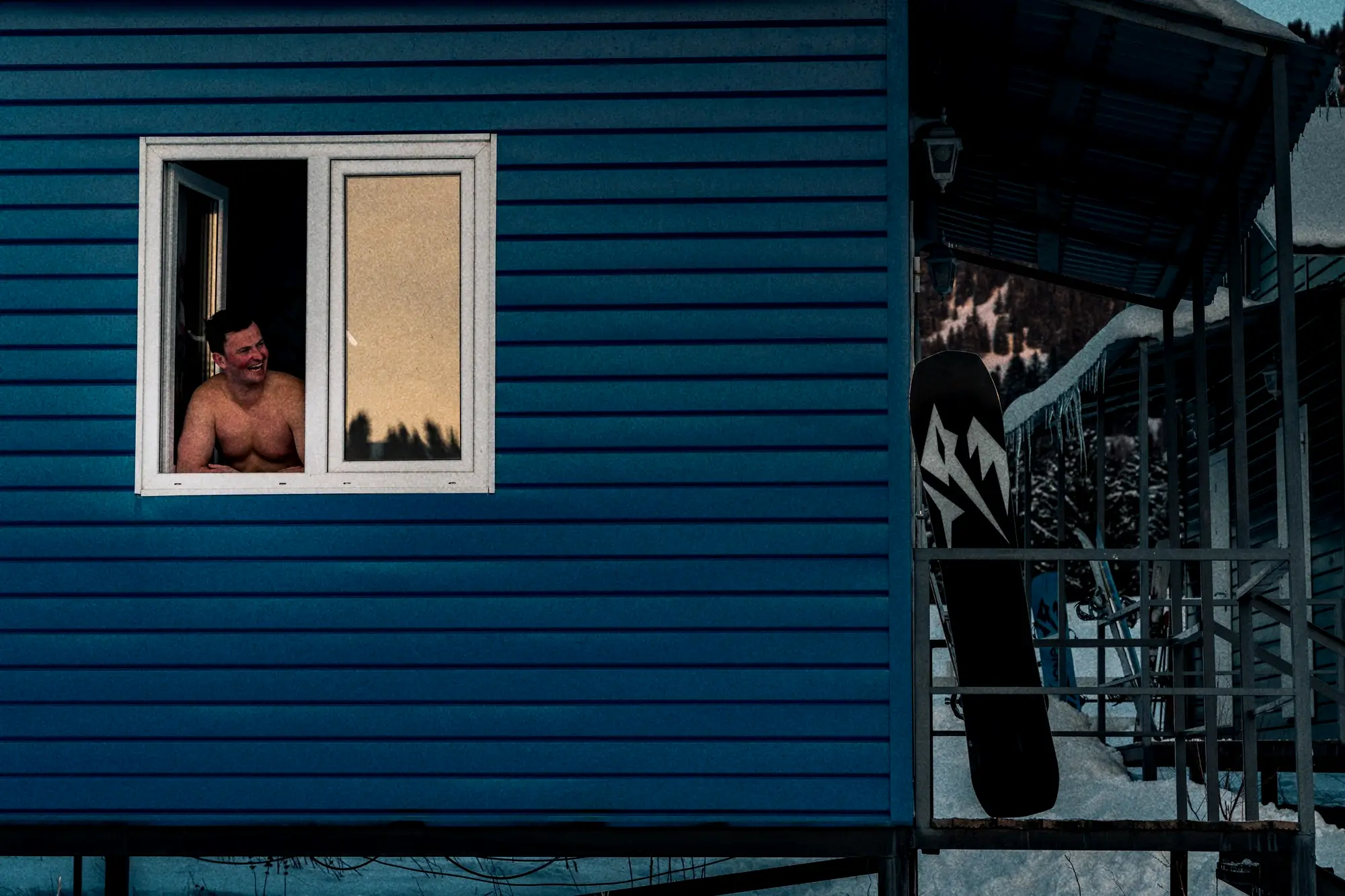 Een gast kijkt uit het raam van de blauwe hut in het base camp