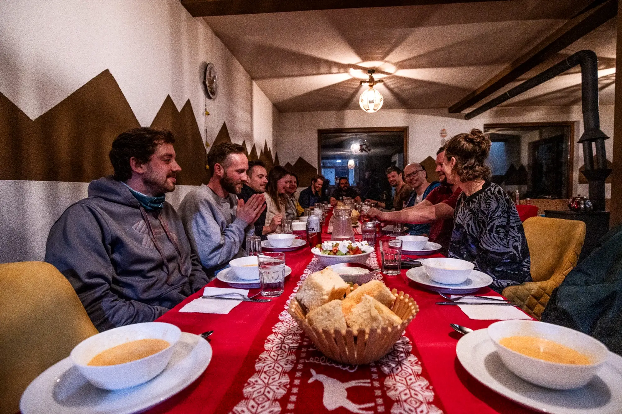 Groep aan een lange tafel met soep en brood in de berghut