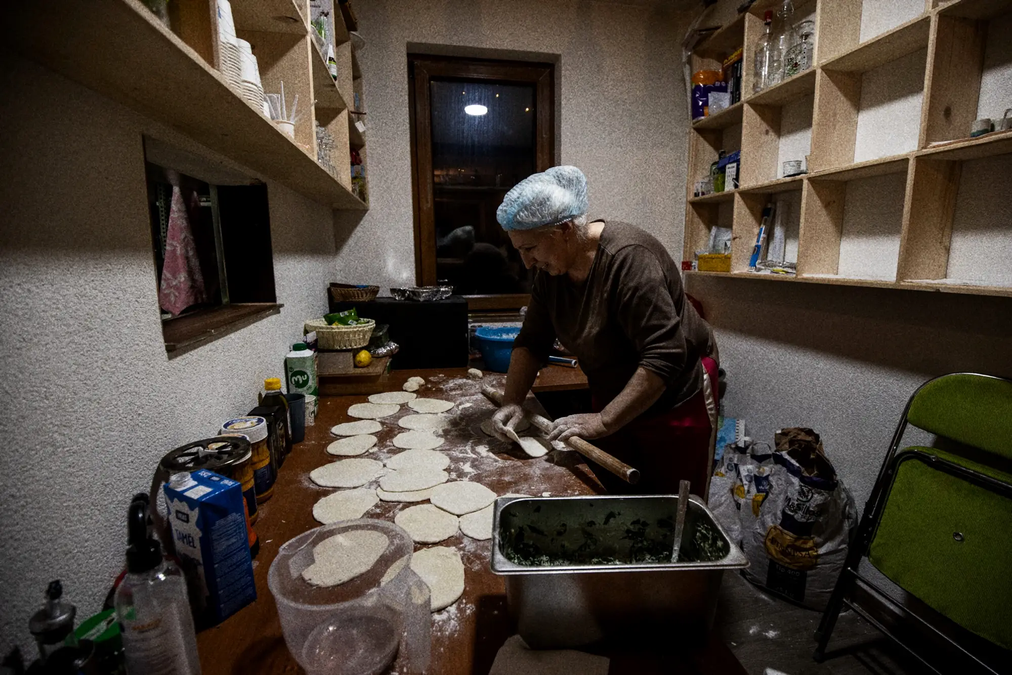Vrouw rolt deeg uit in de keuken van de berghut